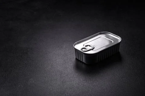 Tin or aluminum rectangular can of canned food with a key on a dark concrete  Foto stock