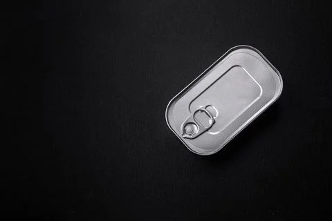Tin or aluminum rectangular can of canned food with a key on a dark concrete  Foto stock