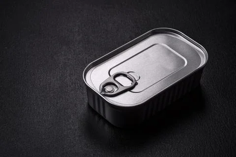 Tin or aluminum rectangular can of canned food with a key on a dark concrete  Foto stock