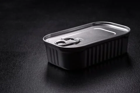 Tin or aluminum rectangular can of canned food with a key on a dark concrete  Foto stock