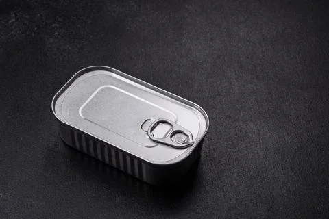 Tin or aluminum rectangular can of canned food with a key on a dark concrete  Foto stock