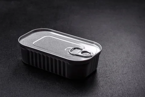 Tin or aluminum rectangular can of canned food with a key on a dark concrete  Foto stock