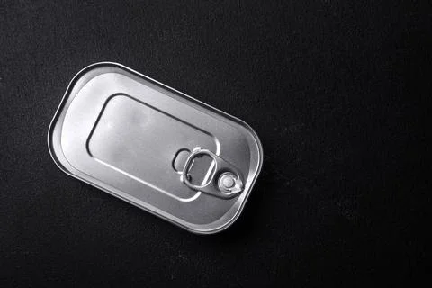 Tin or aluminum rectangular can of canned food with a key on a dark concrete  Stock Photos