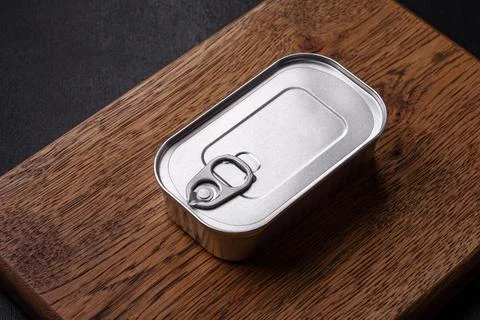 Tin or aluminum rectangular can of canned food with a key on a dark concrete  Stock Photos