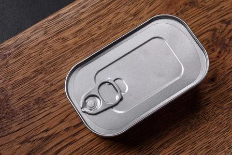 Tin or aluminum rectangular can of canned food with a key on a dark concrete  Foto stock