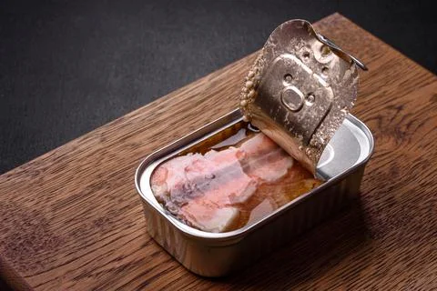 Tin or aluminum rectangular can of canned salmon with a key on a dark concret Stock Photos