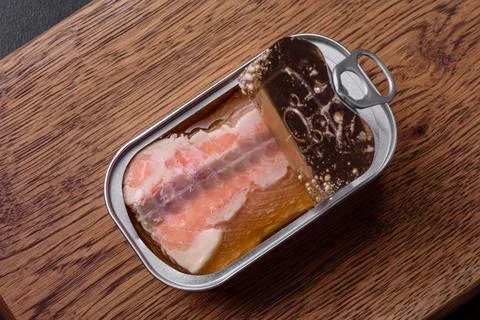 Tin or aluminum rectangular can of canned salmon with a key on a dark concret Stock Photos
