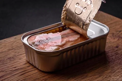 Tin or aluminum rectangular can of canned salmon with a key on a dark concret Stock Photos