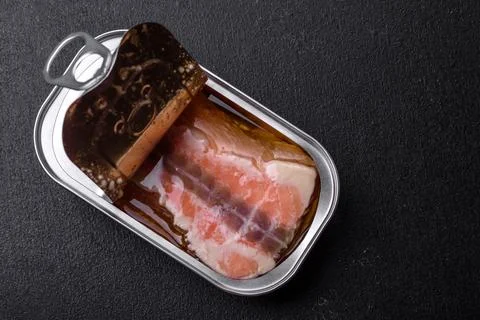 Tin or aluminum rectangular can of canned salmon with a key on a dark concret Stock Photos