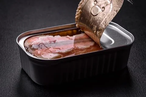 Tin or aluminum rectangular can of canned salmon with a key on a dark concret Stock Photos