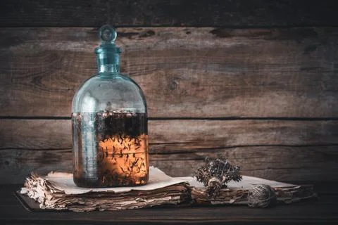 Tincture or potion bottle, old book and bunch of dry healthy herbs.  库存照片
