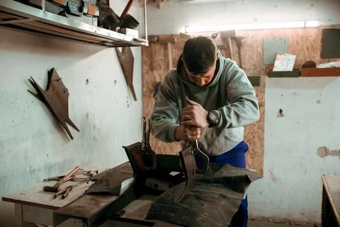 Tinsmith blacksmith use hammer working in his workshop. Stock Photos