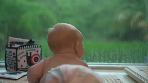 Tiny 3-month-old baby lying on the floor by a large panoramic window, peacefully Video stock 312357424