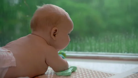 Tiny 3-month-old baby lying on the floor by a large panoramic window, peacefully Video stock 316623966