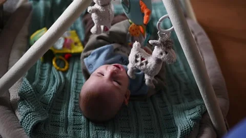 Tiny baby boy lies among vibrant toys, exploring his colorful play area Stock Footage 262738498