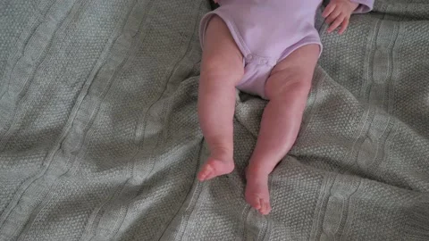 Tiny baby feet top view. Newborn baby girl lying on pastel grey background Video stock 219944773