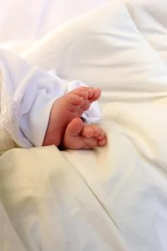 Tiny baby feet wrapped in a soft white blanket during a baptism celebration. Stock Photos