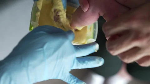Tiny baby foot is put into the yellow stuff in the container.  Video stock 250218792