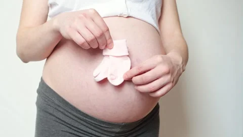 Tiny baby socks against the background of a pregnant belly, pink socks Stock-Footage 306150163
