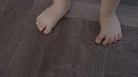 Tiny barefoot legs doing first steps, learning balancing stand still near window Stock-Footage 240346842