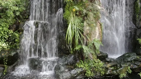 A tiny beautiful artificial waterfall in a garden. Stock Footage 81641330
