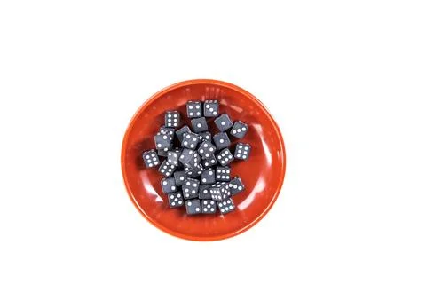 Tiny black and white dice pile in a red bowl isolated over white top down Stock Photos