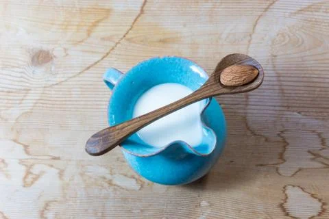Tiny blue ceramic pitcher of almond milk, centered, wood spoon Stock Photos