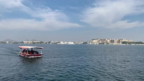 Tiny boat sails in Lake Pichola. Udaipur city Palace and Taj Lake Palace. India Stock Footage 229814508