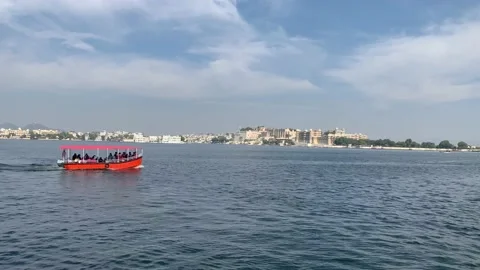Tiny boat sails in Lake Pichola. Udaipur city Palace and Taj Lake Palace. India Stock Footage 229816879