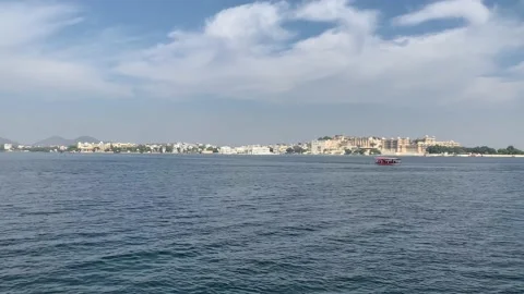 Tiny boat sails in the Lake Pichola. Udaipur city Palace, Taj Lake Palace. India Stock Footage 229818022
