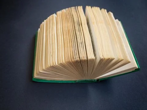 Tiny book lying on a dark paper surface opened like a fan Foto stock