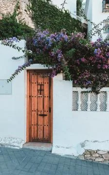 Tiny brown door on a white wall outside in Spain. Entrance to the local house. Stock Photos