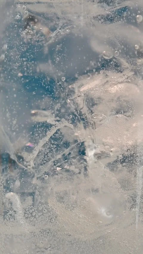 Tiny bubbles rising in chilled sparkling water with ice cubes create a Stock Footage 306166088