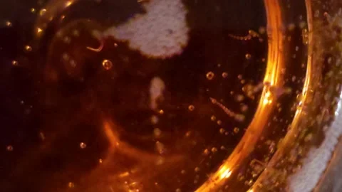 Tiny bubbles rising in golden liquid from bottom of wine glass Stock Footage 310928137