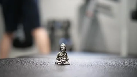 Tiny Buddha in focus with a man in the background doing various house chores Vidéo 278482845