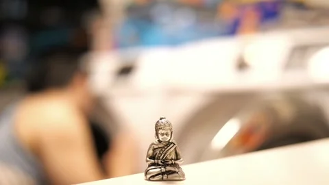 Tiny Buddha in focus with a man in the background doing various house chores Vidéo 278482846