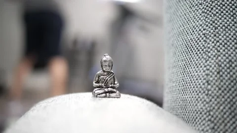 Tiny Buddha in focus with a man in the background doing various house chores Vidéo 278482847