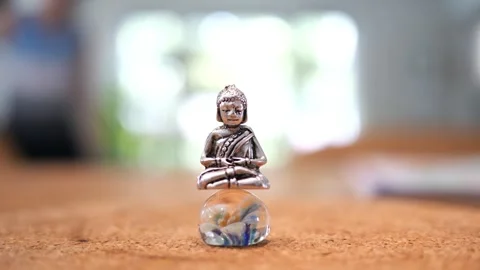 Tiny Buddha in focus with a man in the background doing various house chores Vidéo 278482848