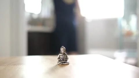 Tiny Buddha in focus with a man in the background doing various house chores Vidéo 278544257