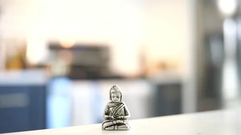 Tiny Buddha in focus with a man in the background doing various house chores Vidéo 278544261