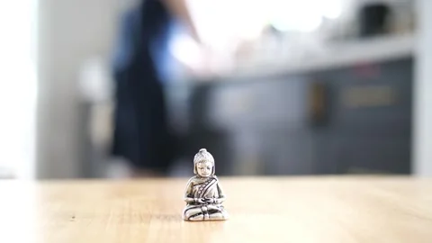 Tiny Buddha in focus with a man in the background doing various house chores Vidéo 278544287