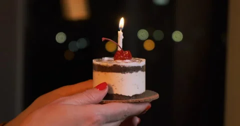 Tiny cake with a cherry, blowing candle. Wishing, celebrating a happy birthday. Stock-Footage 149894617