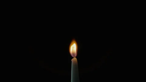 Tiny candle staying black background in stillness. Wax taper burning on dark Stock Footage 332506363