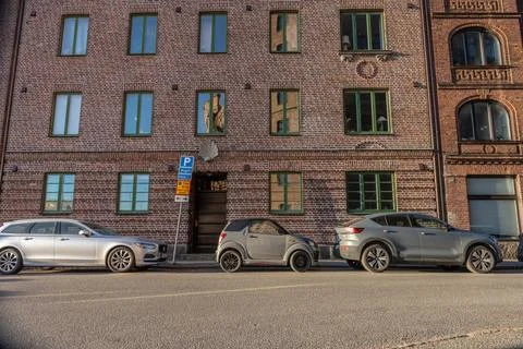 Tiny car parked by tow normal sized cars by a building Stock Photos