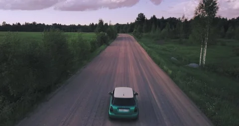 Tiny car rolling on a dirt road surrounded by green fields Video stock 124645912