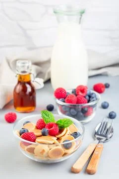 Tiny cereal pancakes served with maple syrup, raspberry, blueberry and milk 스톡 사진