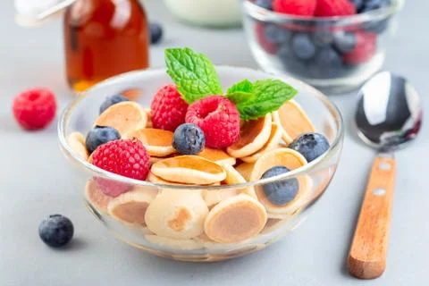 Tiny cereal pancakes served with maple syrup, raspberry, blueberry and milk 스톡 사진