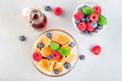 Tiny cereal pancakes served with maple syrup, raspberry and blueberry 스톡 사진