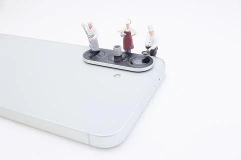 Tiny Chef Figurines Standing on Smartphone Camera Bar Foto stock