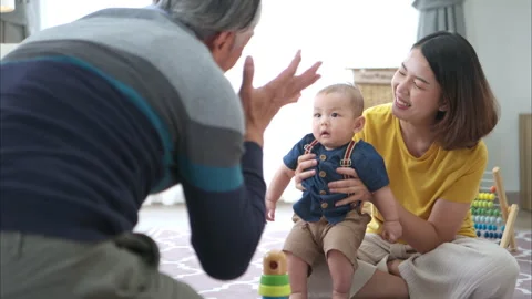 A tiny child cheerfully plays with toys with mom and grandfather Stock Footage 287972063
